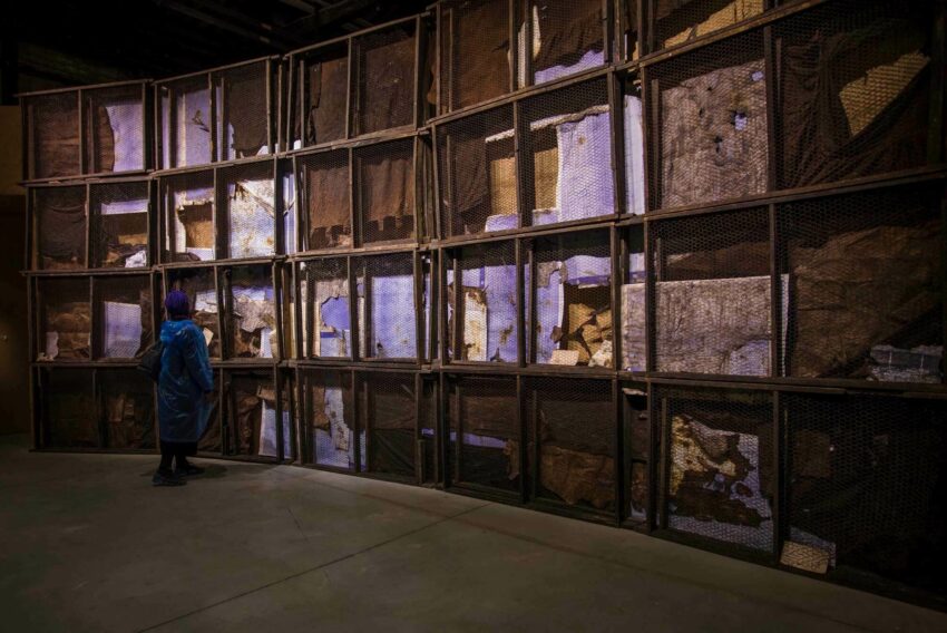 Installation view with various objects behind fencing.